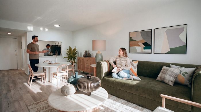 Bright, modern apartment living room with stylish decor, featuring a cozy green sofa and open dining area ideal for social gatherings.
