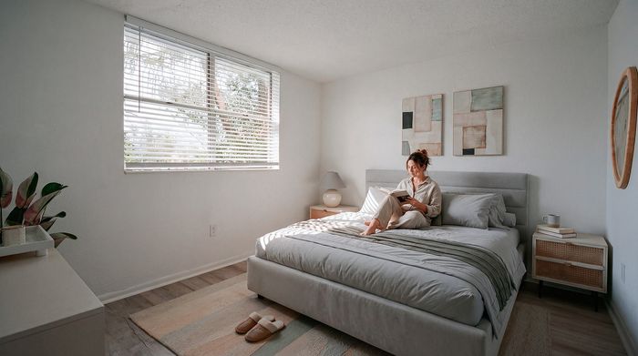 Bright, cozy bedroom with a large window, a stylish gray bed, and a relaxed atmosphere. Ideal retreat for reading and relaxation.