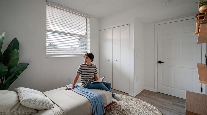 Bright, inviting bedroom with a cozy bed, modern furnishings, and large window offering ample natural light.