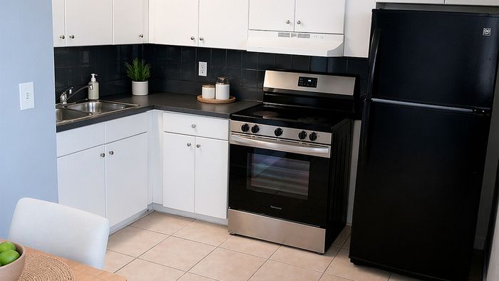 Chic and modern kitchen with sleek black appliances, white cabinetry, and spacious countertops.