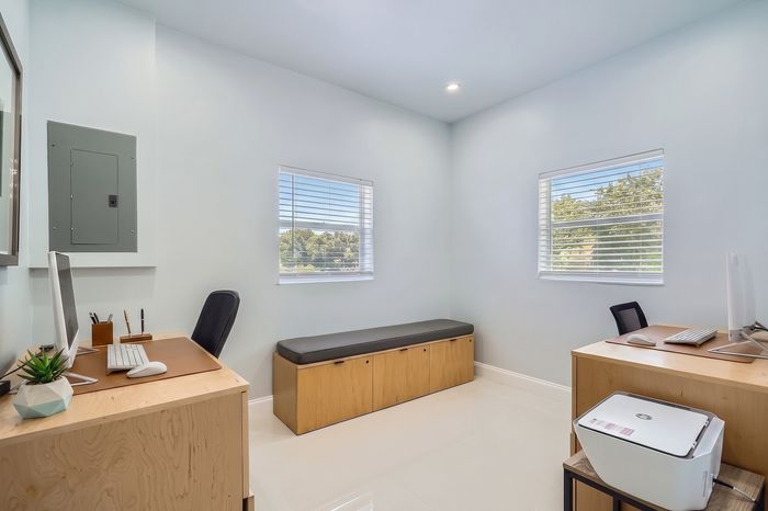 Bright and modern home office with dual desks, ample natural light, and sleek furnishings, perfect for productivity and comfort.