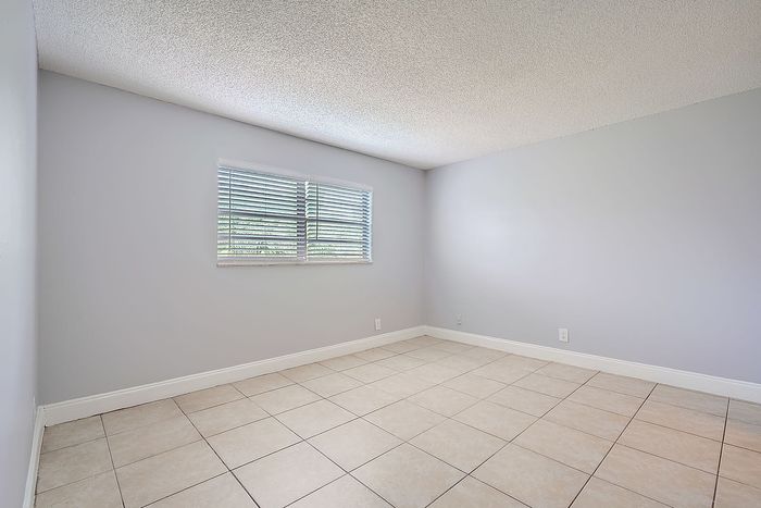 Bright, spacious empty room with modern light gray walls and large window, perfect for customization and personal touch.