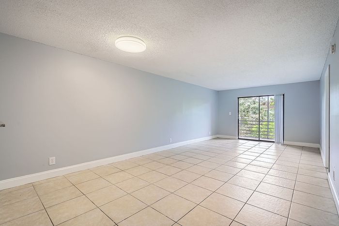 Bright and spacious room with large windows, offering an inviting view of greenery and ample natural light, perfect for a cozy living area.