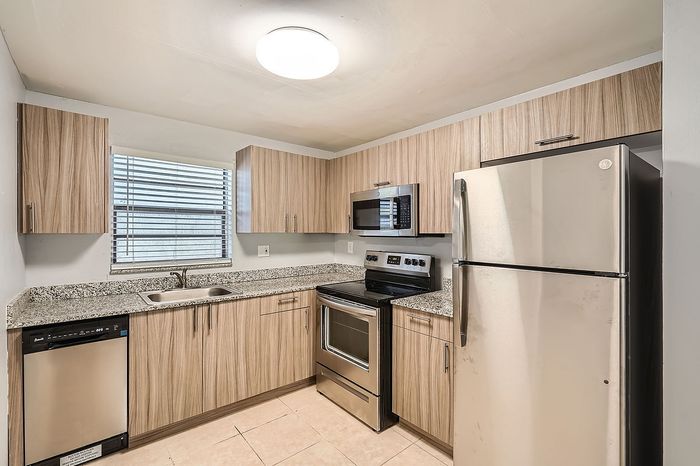 Modern kitchen with sleek stainless steel appliances and chic wooden cabinetry, perfect for culinary enthusiasts.
