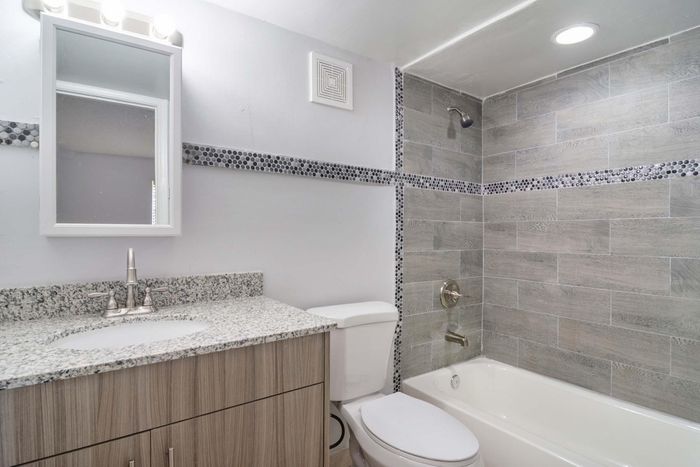 Modern bathroom with elegant gray tile design, sleek granite countertop, and stylish fixtures.