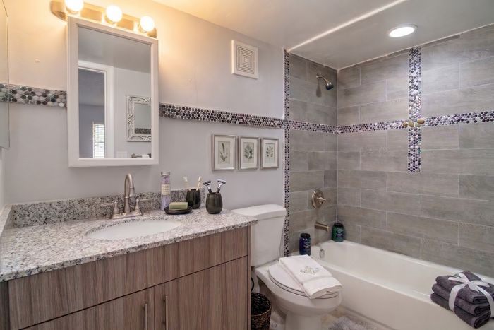 Elegant modern bathroom featuring a stylish gray tiled wall, a sleek granite countertop, and soft ambient lighting.