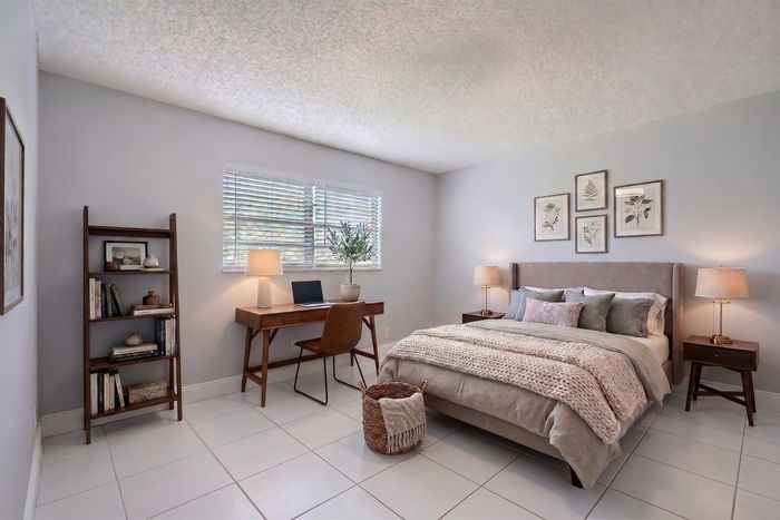 Charming bedroom with natural light, cozy bed, modern desk setup, and elegant decor.