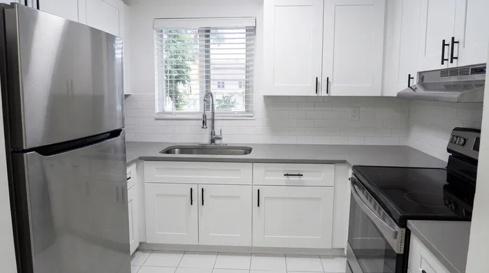 Modern kitchen with stainless steel appliances, sleek gray countertops, and elegant white cabinetry.