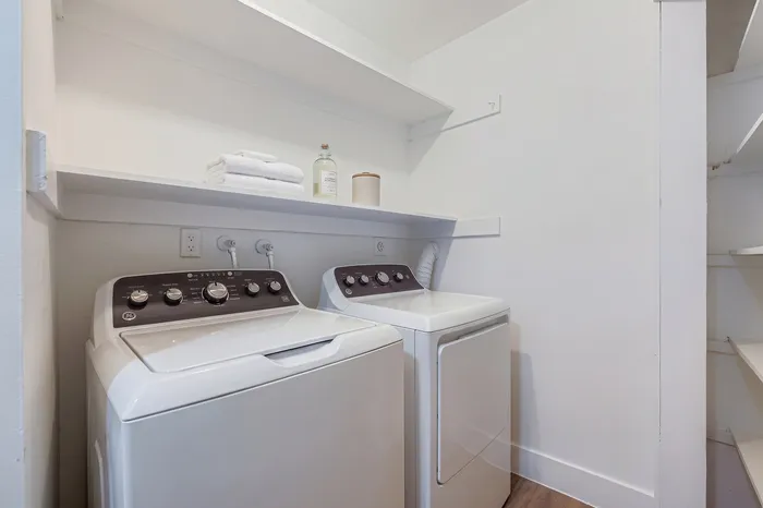 Modern laundry room with sleek washer and dryer, ample shelving, and a bright, organized space.