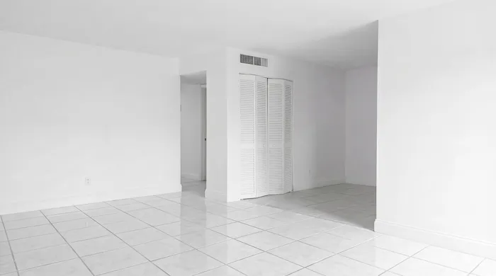 Bright and spacious tiled room with pristine white walls and modern closet doors, offering a versatile open space.
