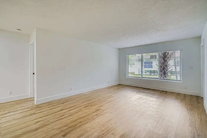 Bright and airy living space with modern wooden flooring, large windows offering scenic views, and freshly painted walls.