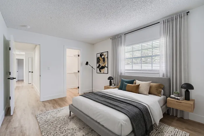 Cozy bedroom with modern decor featuring a plush bed, elegant side tables, and natural light streaming through the window.