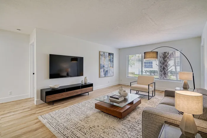 Bright and modern living room with sleek wooden floors, elegant decor, and abundant natural light through large windows.