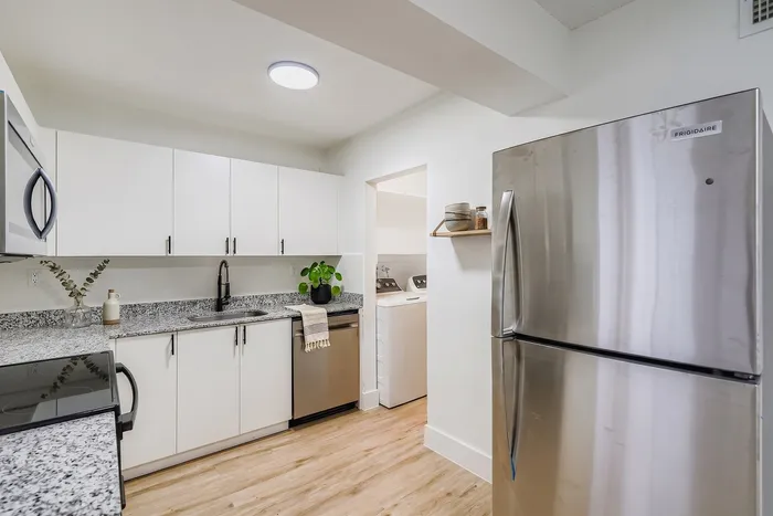 Modern kitchen with sleek stainless steel appliances, elegant white cabinetry, and stylish granite countertops.