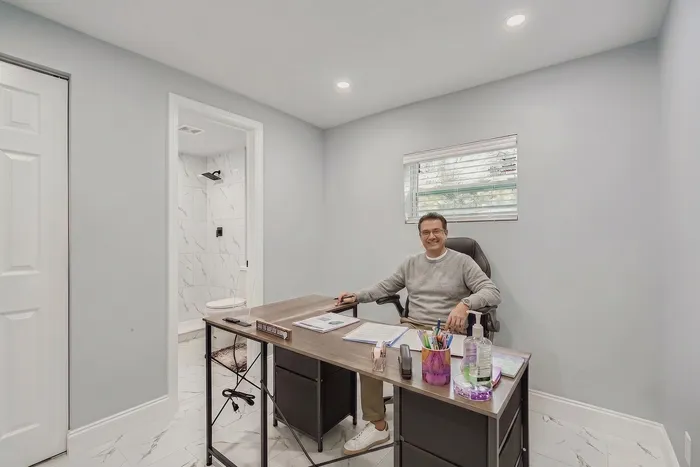 Bright and modern office space with elegant tiled floors, featuring a professional desk setup and an adjoining chic bathroom.