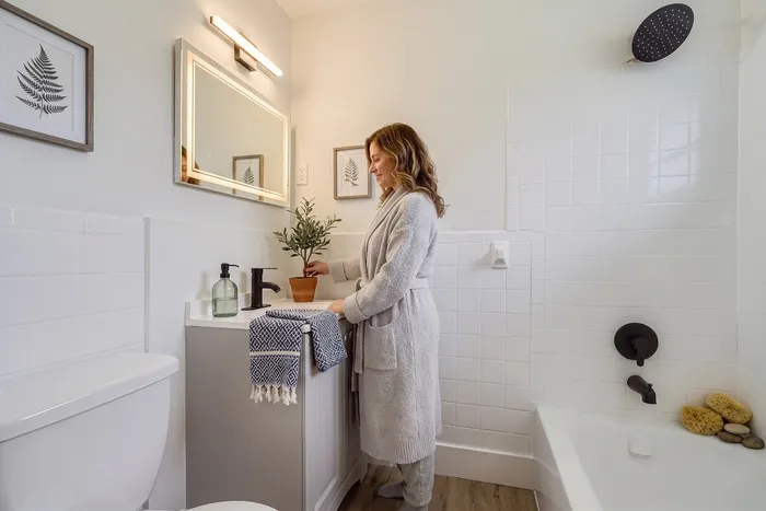 Elegant bathroom scene with modern fixtures, a large mirror, stylish decor, and a relaxing tub.