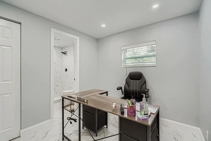 Bright and modern home office with sleek desk and comfortable chair, featuring an elegant en suite bathroom.