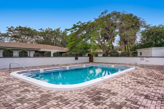 Charming residential complex with a sparkling pool, surrounded by lush greenery and inviting walkways.