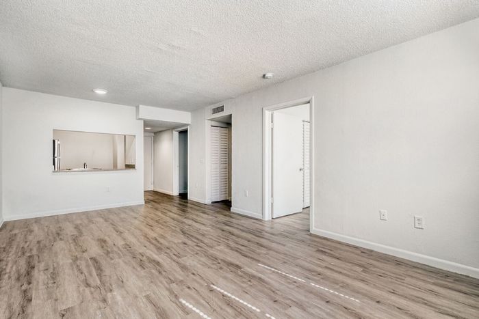 Bright and spacious living area with elegant wood flooring and open kitchen access.