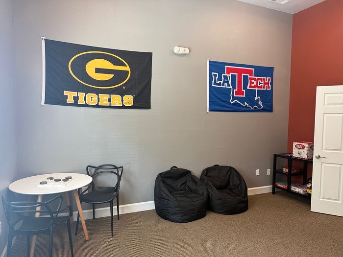 Cozy recreational room with vibrant college flags, modern table and chairs, and plush bean bags for relaxation.