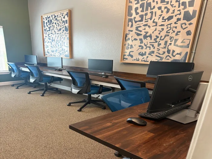 Modern workspace with sleek computers, ergonomic chairs, and abstract art on the walls for a creative and productive environment.