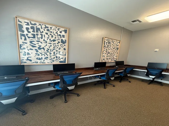 Modern workspace featuring sleek computer stations with blue ergonomic chairs and stylish abstract artwork.