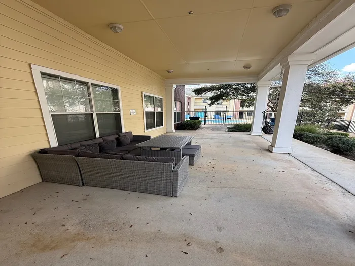 Charming apartment patio with cozy seating and a view of lush greenery, perfect for relaxation.