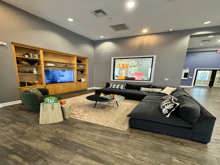 Inviting modern living room with cozy sectional sofa, stylish wooden flooring, built-in shelves, and vibrant wall art.