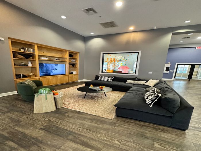 Modern living room with sleek wooden flooring, plush sectional sofa, and built-in entertainment center for a cozy ambiance.