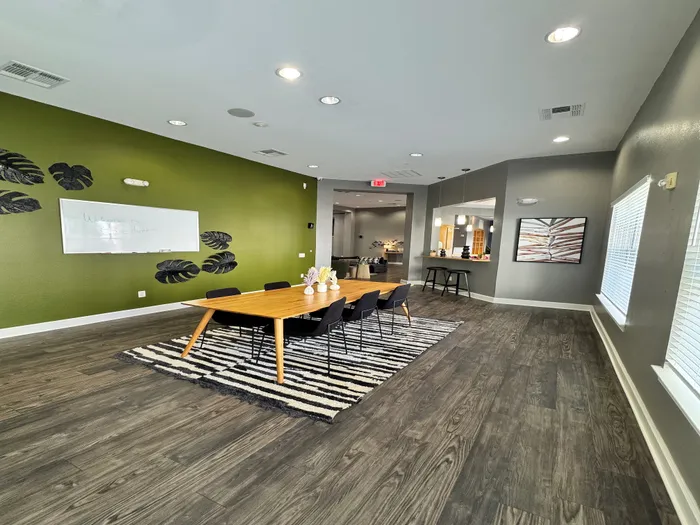 Elegant meeting space with a sleek wooden table, modern black chairs, and vibrant green accent wall, perfect for collaborative discussions.