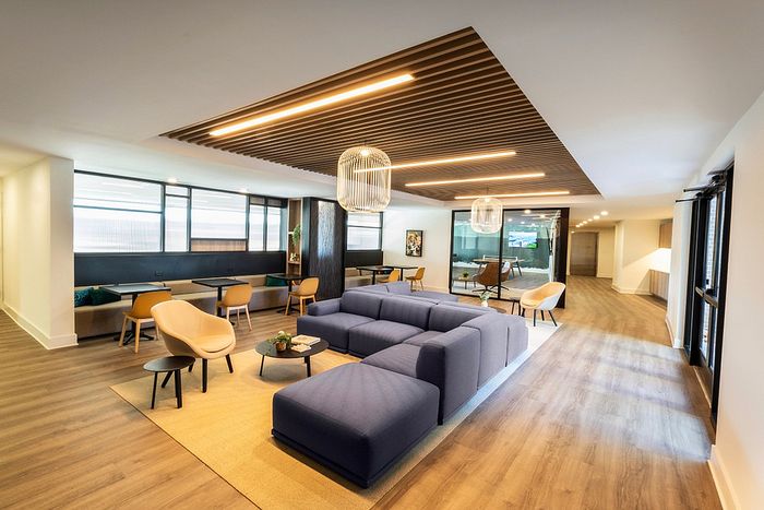 Modern living area featuring sleek wooden flooring, stylish seating with plush blue sectional and elegant lighting, perfect for relaxation and socializing.