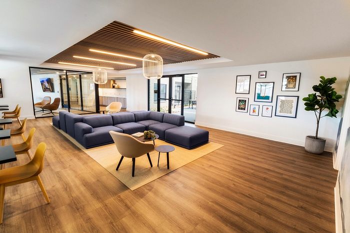 Elegant living room featuring a modern blue sectional sofa, stylish wooden flooring, and chic wall art, with ample natural light and contemporary design accents.