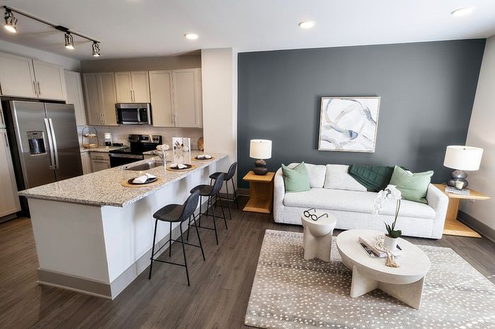 Modern open-plan kitchen and living area boasting elegant granite countertops, stylish bar seating, and cozy seating with contemporary decor.