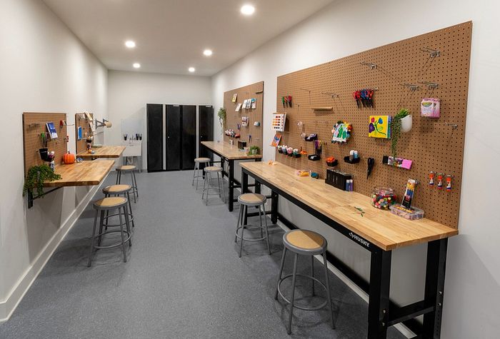 Modern creative workspace with wooden workbenches, pegboard walls, and art supplies, perfect for inspired crafting.
