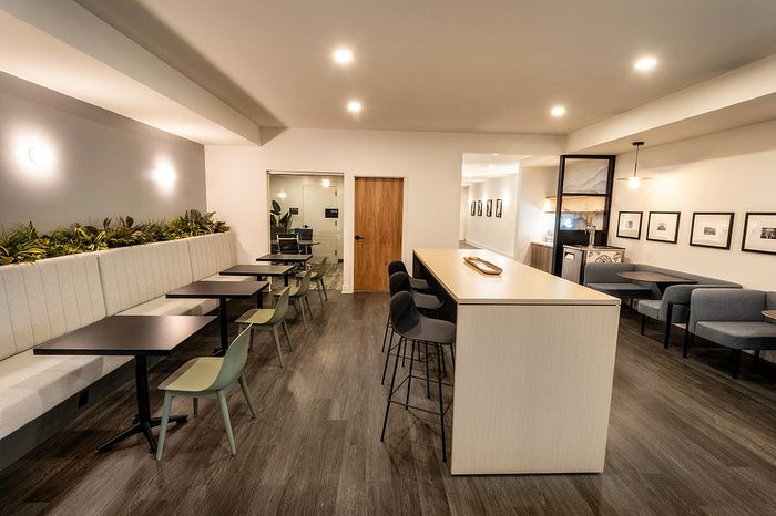 Modern communal dining area with elegant seating, sleek wooden floors, and ambient lighting, perfect for relaxed gatherings.