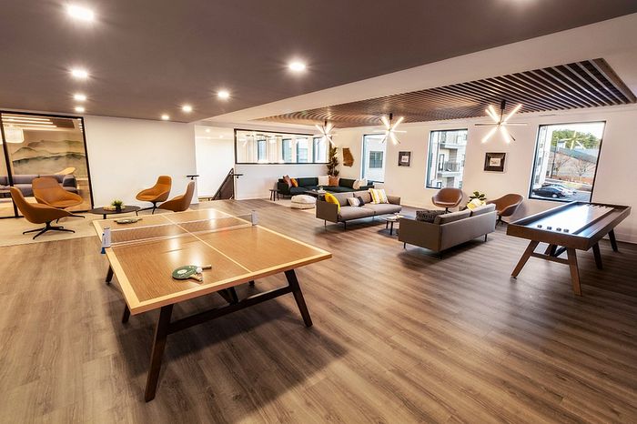 Luxurious lounge featuring modern seating, elegant lighting, and a ping pong table, offering a blend of style and comfort.