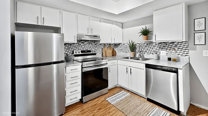 Modern kitchen featuring sleek stainless steel appliances, stylish white cabinetry, and a chic black-and-white mosaic backsplash.