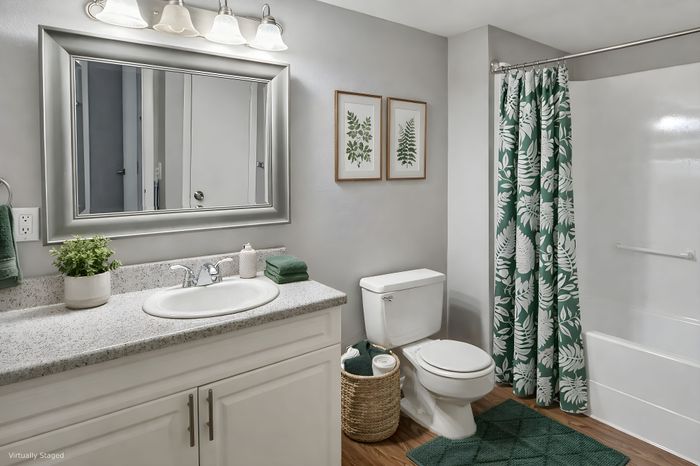 Elegant bathroom with stylish decor featuring a large mirror, granite countertop, and vibrant botanical shower curtain, creating a serene oasis.
