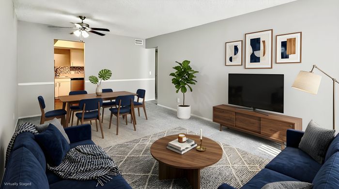 Elegantly staged living and dining area featuring a stylish navy sofa, modern dining set, and minimalist decor with vibrant green plant accents.