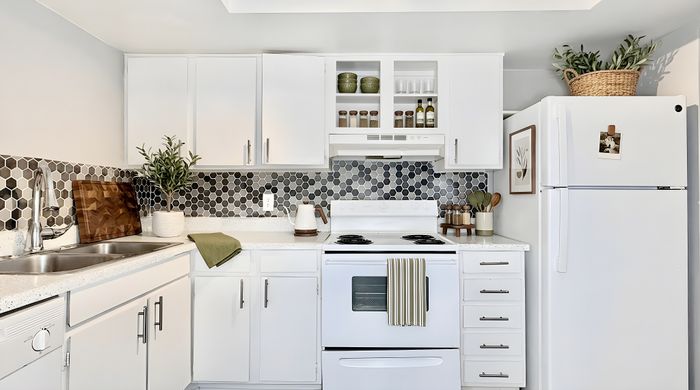 Modern kitchen with sleek white cabinets, hexagonal tile backsplash, and stylish countertop decor.