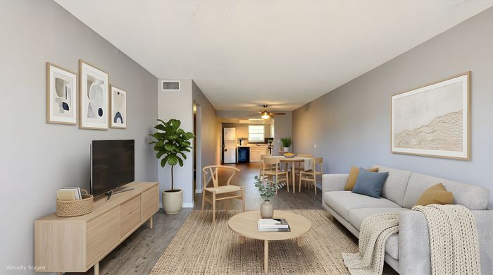 Contemporary open-concept living room with sleek furnishings, cozy seating, and elegant decor leading to a modern kitchen.