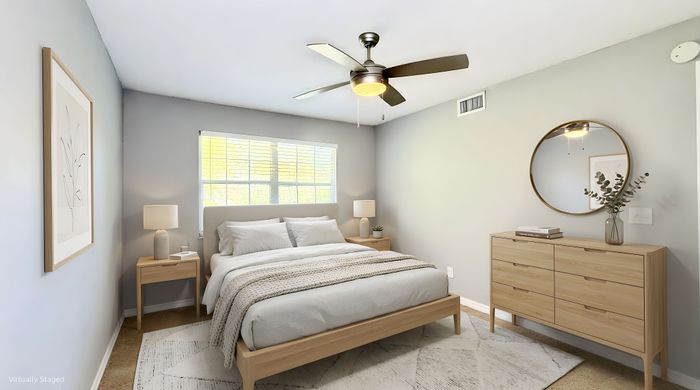 Inviting bedroom with a cozy bed, modern ceiling fan, and stylish wooden furniture, creating a serene and welcoming atmosphere.
