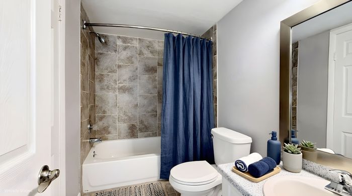 Elegant bathroom with modern tiled shower, sleek vanity, and designer accents featuring plush towels and decorative plants.
