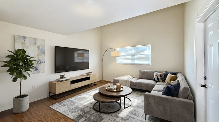 Modern living room with a large flat-screen TV, stylish sectional sofa, and elegant decor, featuring natural light and chic design elements.