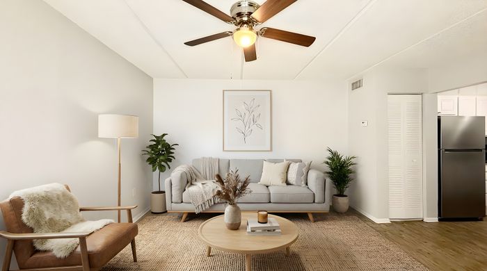 Bright and inviting living room with cozy seating, a chic round coffee table, and a modern ceiling fan accentuating natural light.