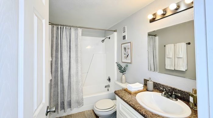 Bright and modern bathroom featuring sleek fixtures, elegant granite countertop, and soothing decor accents.