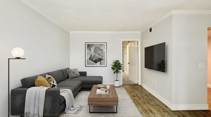 Elegant living room with modern gray sofa, chic artwork, and a sleek wall-mounted TV; perfect for relaxation and entertainment.
