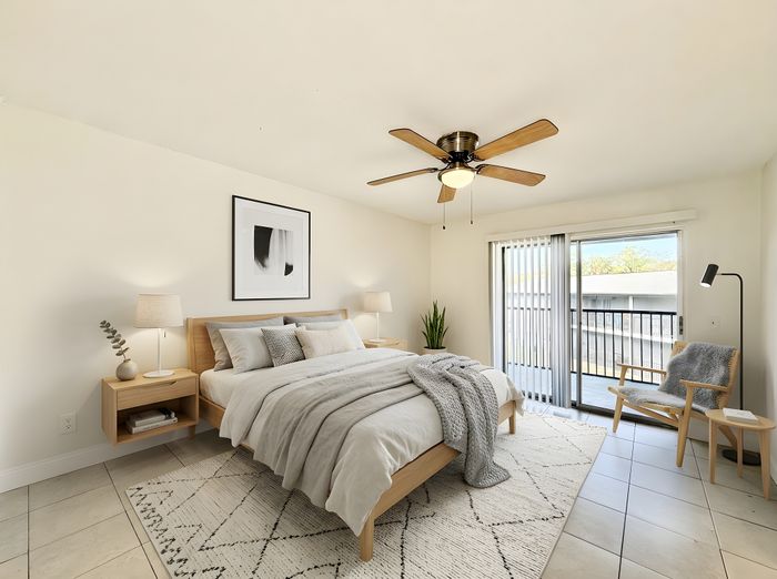 Sunlit bedroom featuring a cozy bed, stylish decor, modern ceiling fan, and a private balcony access.