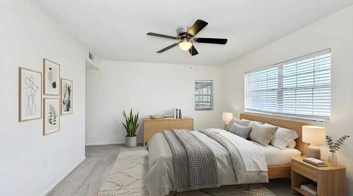 Bright and airy bedroom with elegant decor, featuring modern ceiling fan, stylish artwork, and plush bedding, perfect for relaxation.