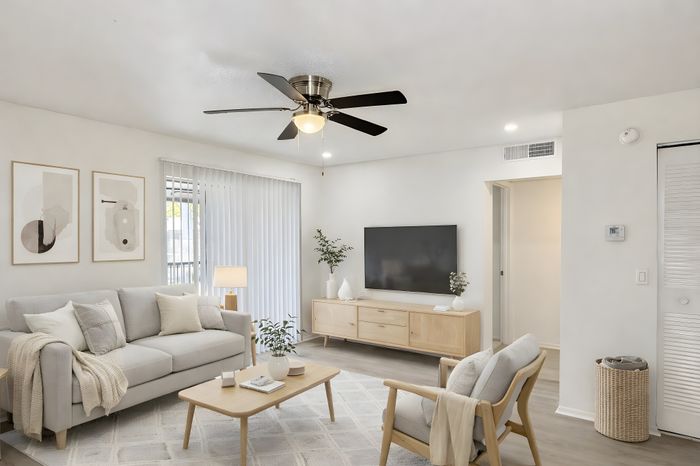 Bright and modern living room with stylish decor, featuring a cozy sofa, sleek TV unit, and elegant ceiling fan.